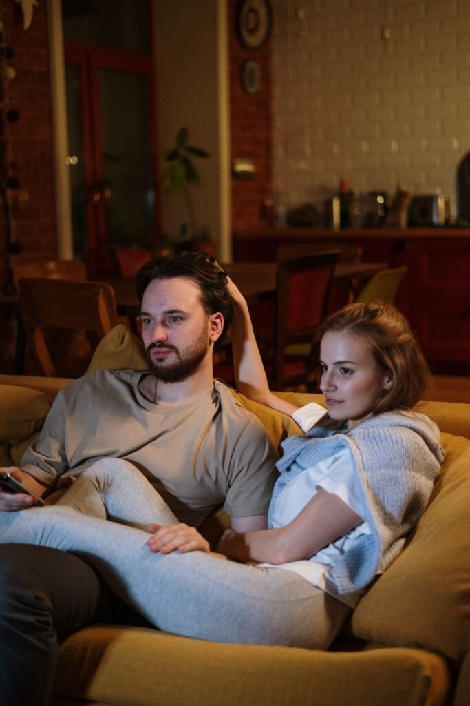 Couple relaxing on a sofa in a cozy, dimly lit living room in the evening